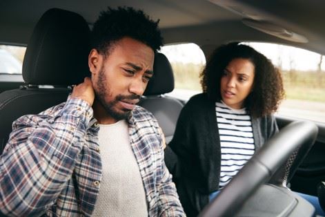 man rubbing injured neck after car accident